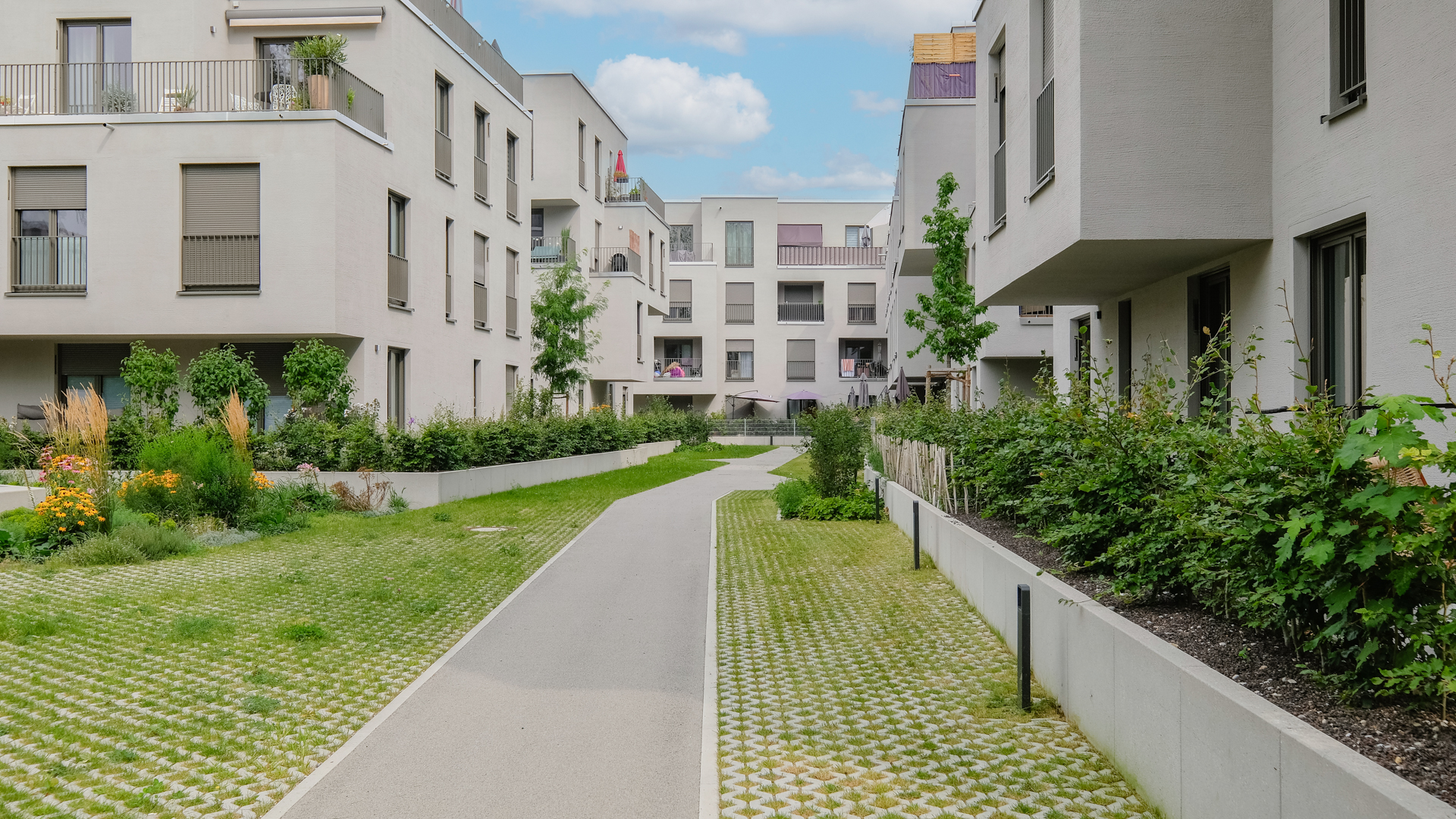 Foto vom Neubau Am Papierbogen mit versprungener Fassade, und Gärten im Vordergrund.